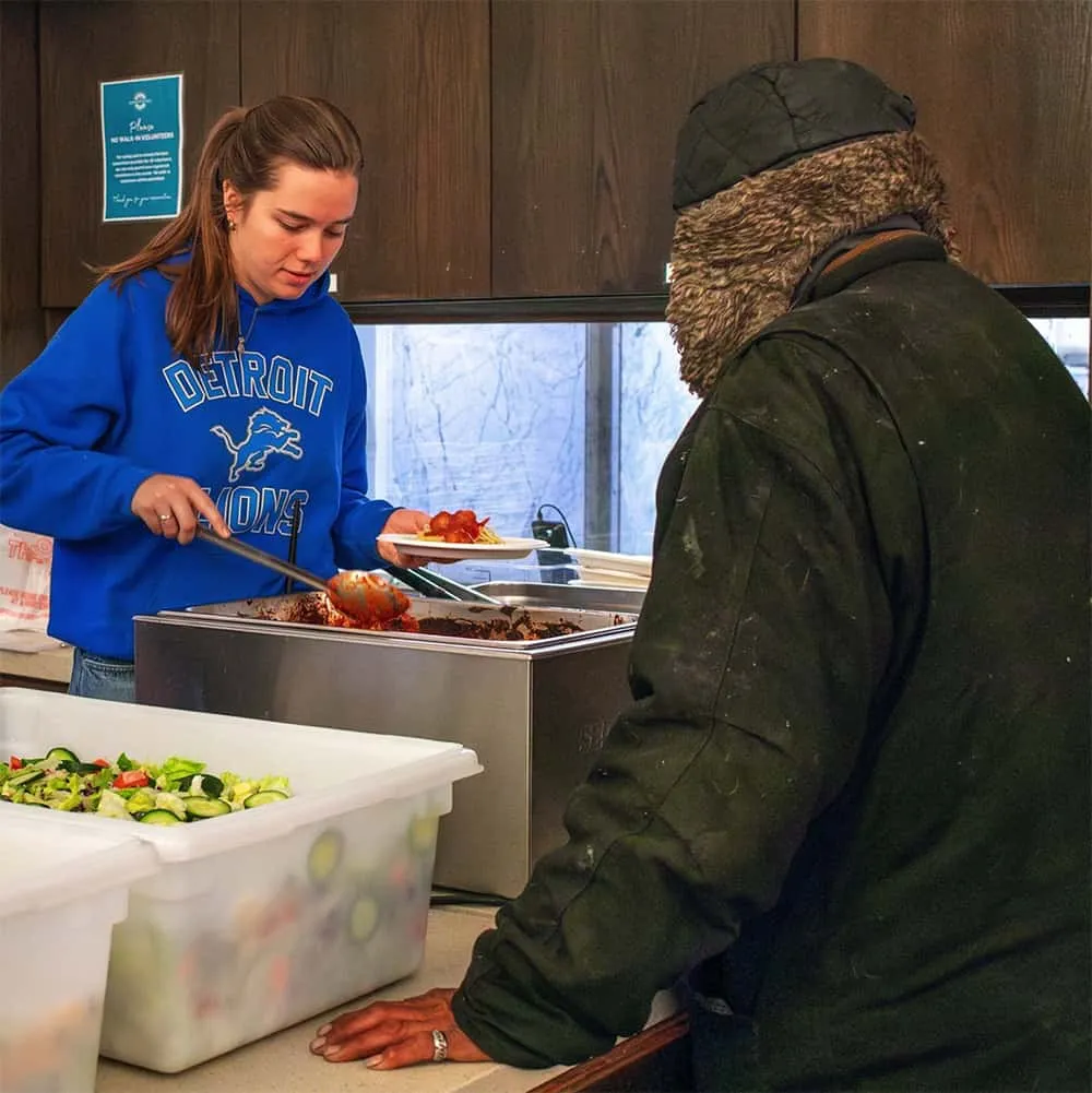 voluntario del centro de día sirviendo ensalada
